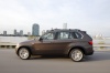 Driving 2013 BMW X5 xDrive50i in Sparkling Bronze Metallic from a left side view